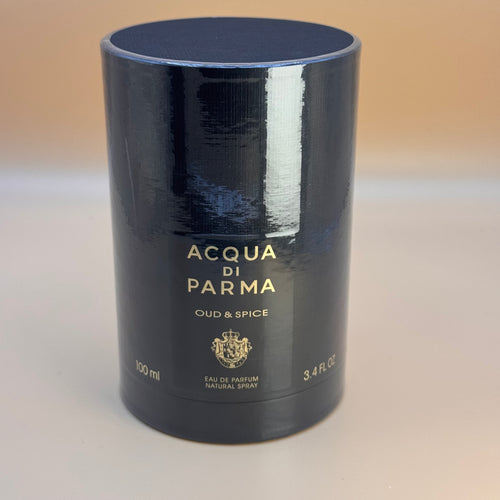 Black cylindrical container of Acqua di Parma Oud & Spice perfume on a beige background