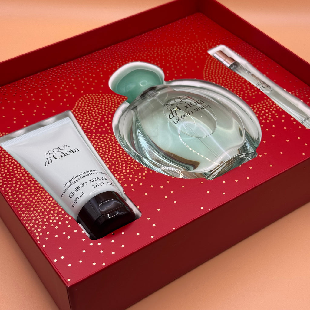 Acqua di gioia set with bottle, spray, and cream in a decorative box on a peach background