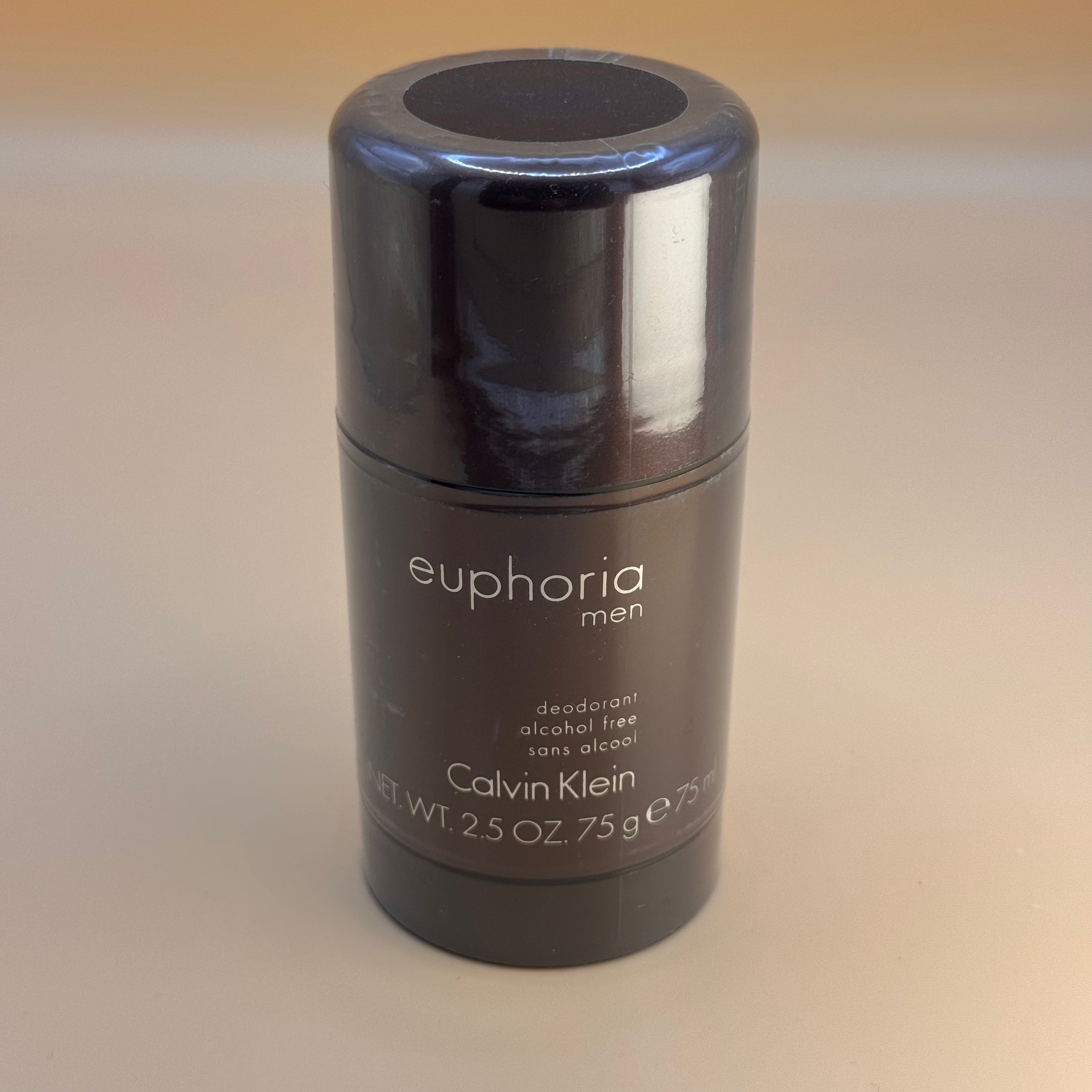 Black deodorant stick with 'euphoria men' and 'Calvin Klein' branding on a beige background