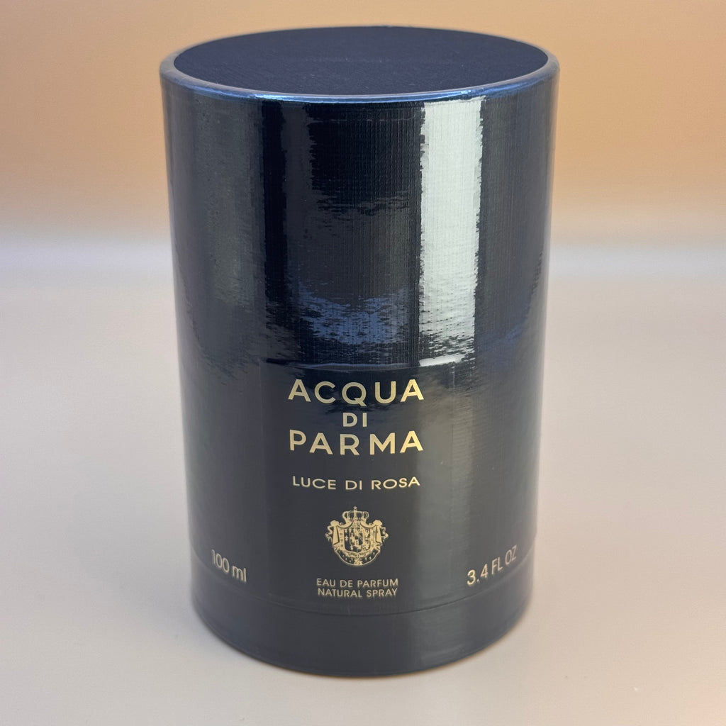 Black cylindrical Acqua di Parma Luce di Rosa perfume bottle on a beige background