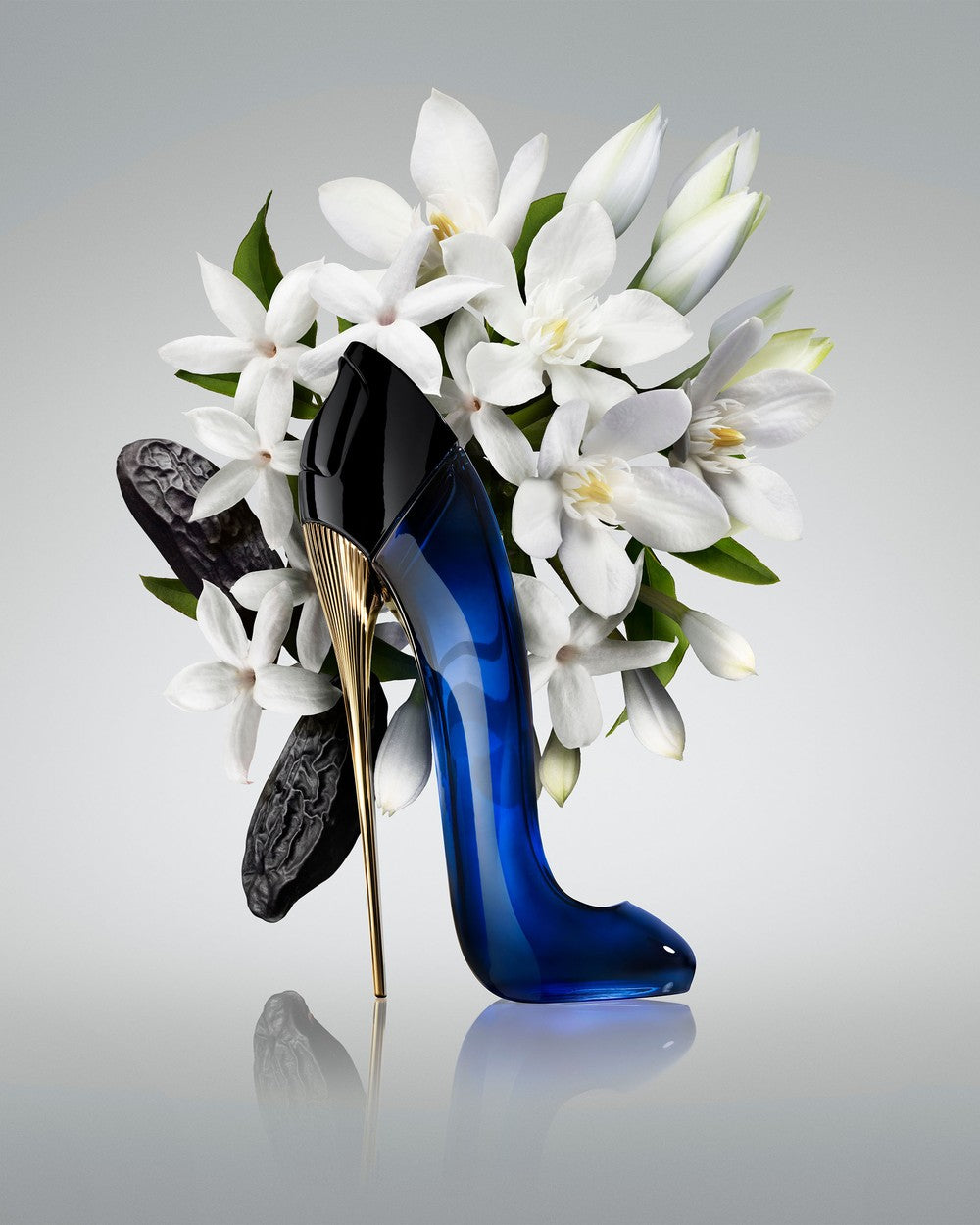 Blue high-heeled shoe with gold heel on a gray background with white flowers